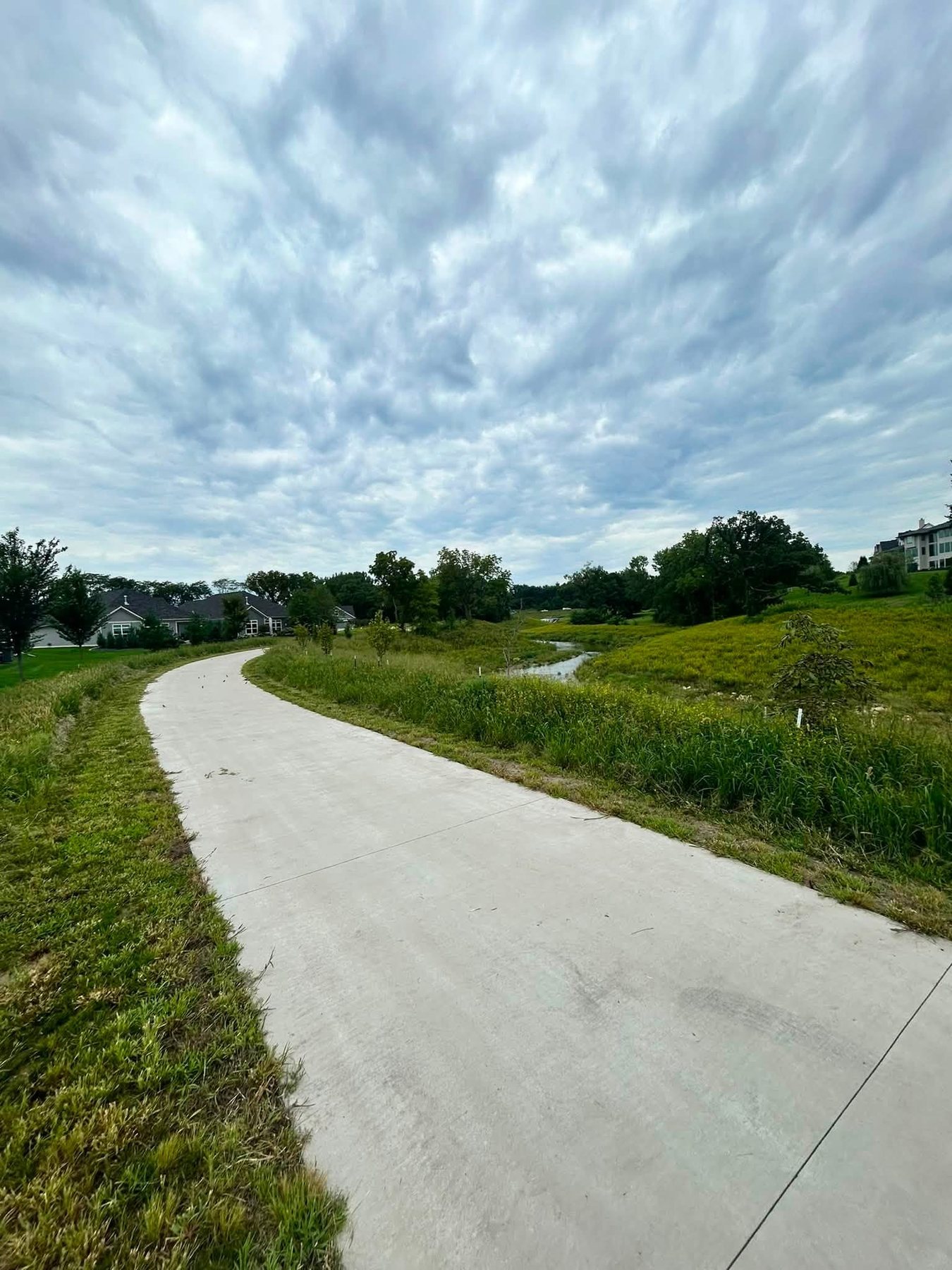 Curving concrete path through a green space