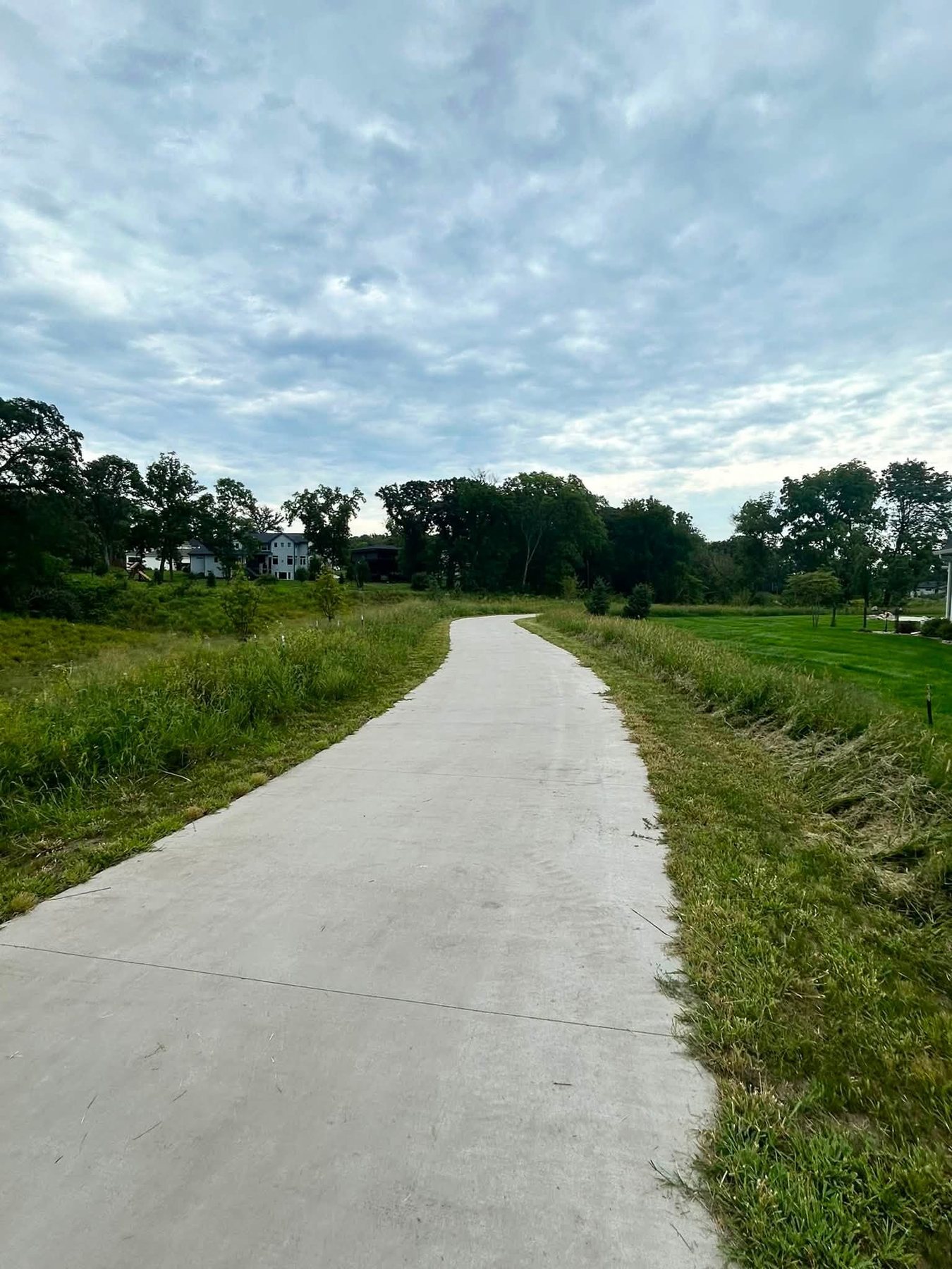 Completed concrete path extending through open green space